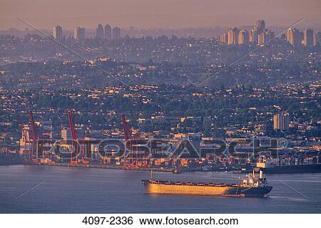 Stock Photograph - Container ship in the sea at sunset, Burrard Inlet, Vancouver, British Columbia, Canada. Fotosearch
