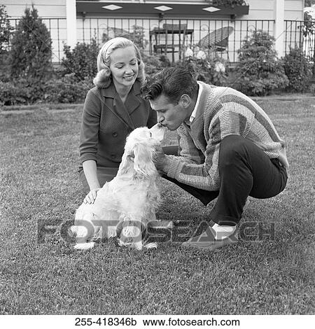 Stock Image - Couple playing with dog. Fotosearch