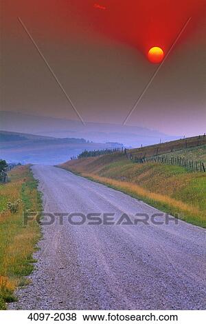 Stock Photo - Dirt road passing through a landscape with mountains in the background, Canadian Rockies, Alberta, Canada. Fotosearch