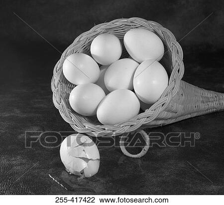 Stock Image - Eggs in the basket, on the foreground broken egg. Fotosearch