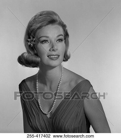 Stock Image - Elegant young woman smiling and looking away, studio shot. Fotosearch