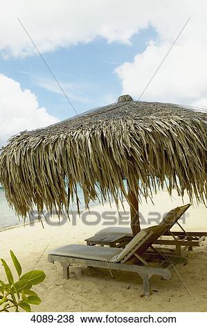 Stock Photo - Empty lounge chairs under a palapa on the beach, Bora Bora, Society Islands, French Polynesia. Fotosearch