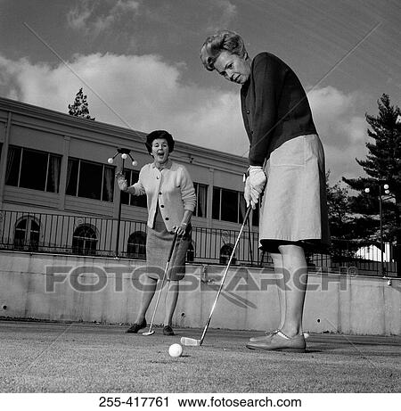 Stock Image - Excited woman watching while other is playing golf. Fotosearch