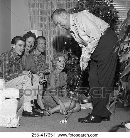 Family near Christmas tree watching man playing mini golf View Large Photo Image Stock Image - Family near Christmas tree watching man playing mini golf. Fotosearch