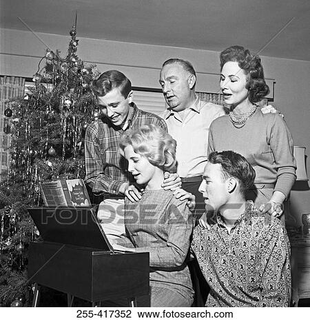 Stock Image - Family playing and singing Christmas carols. Fotosearch
