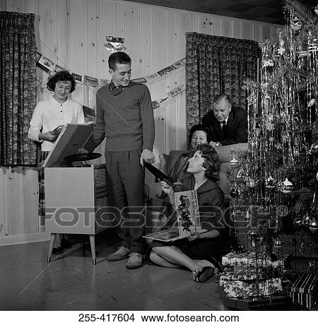 Picture - Family playing records on record player by Christmas tree. Fotosearch
