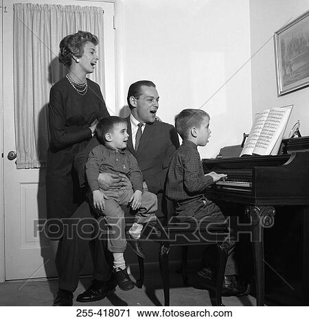 Stock Image - Family signing by with boy playing piano. Fotosearch