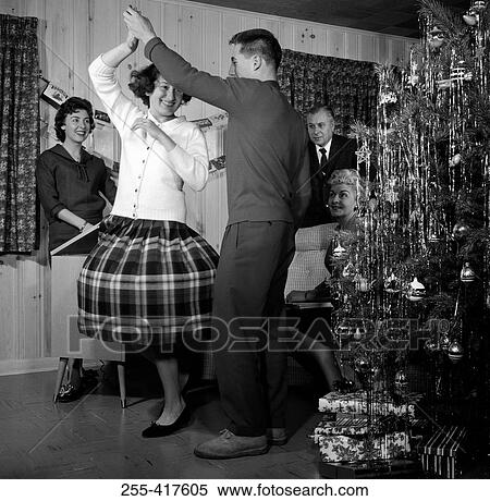 Family watching couple dancing by Christmas tree View Large Photo Image Stock Photography - Family watching couple dancing by Christmas tree. Fotosearch