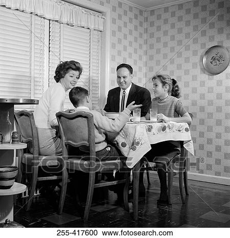 Stock Image - Family with children talking at dining table. Fotosearch