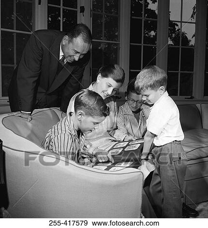 Family with three boys viewing photograph album in living room View Large Photo Image Stock Photo - Family with three boys viewing photograph album in living room. Fotosearch