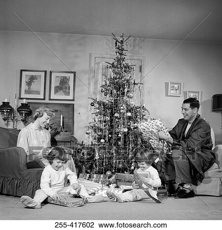 Family with two children opening gifts by Christmas tree View Large Photo Image Stock Image - Family with two children opening gifts by Christmas tree. Fotosearch