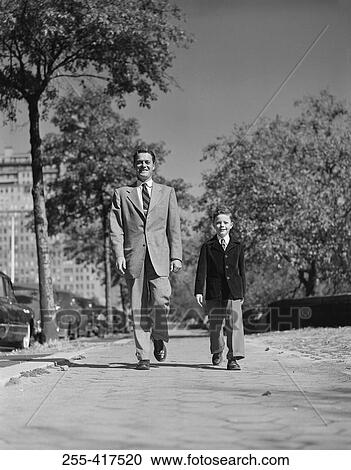 Stock Image - Father and son walking through park. Fotosearch