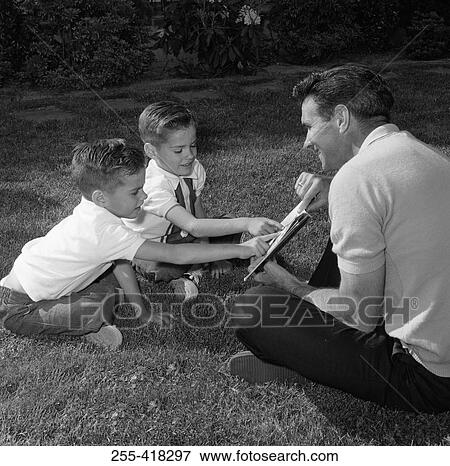 Father with twin sons reading book sitting on lawn View Large Photo Image Stock Photo - Father with twin sons reading book sitting on lawn. Fotosearch