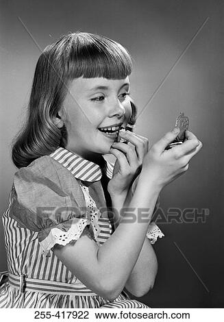 Stock Image - Girl putting lipstick on. Fotosearch