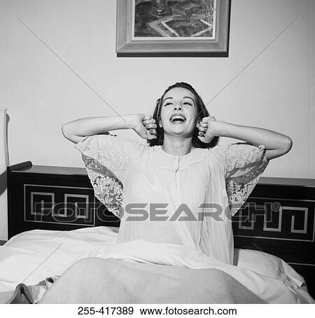 Stock Photo - Happy young woman stretching in bed. Fotosearch