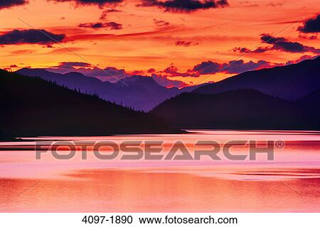 Stock Image - Lake with mountains in the background at dusk, Medicine Lake, Colin Range, Jasper National Park, Alberta, Canada. Fotosearch