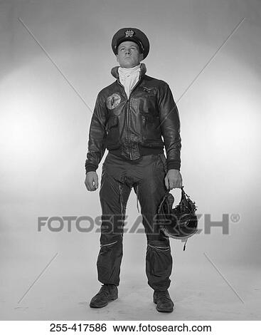 Stock Photograph - Male pilot holding helmet, looking up. Fotosearch