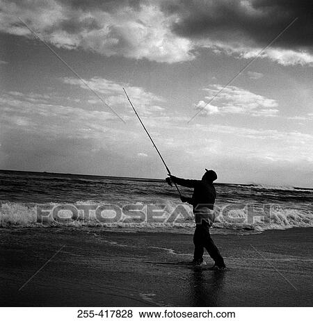 Stock Photo - Man fishing at the edge of water. Fotosearch