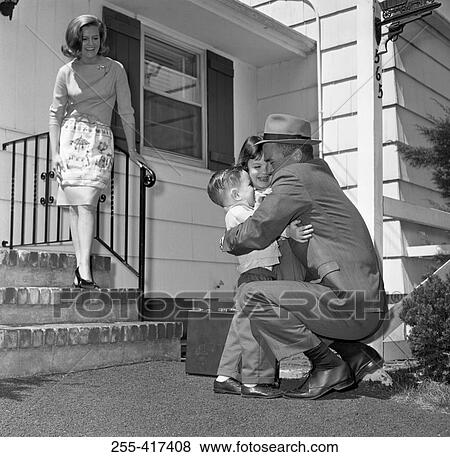 Stock Photo - Mature man embracing children, wife standing on doorsteps and looking at them. Fotosearch