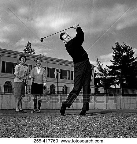 Stock Image - Mature man plying golf while pair of women is watching. Fotosearch