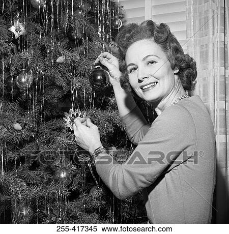 Stock Photography - Mature woman decorating Christmas tree. Fotosearch