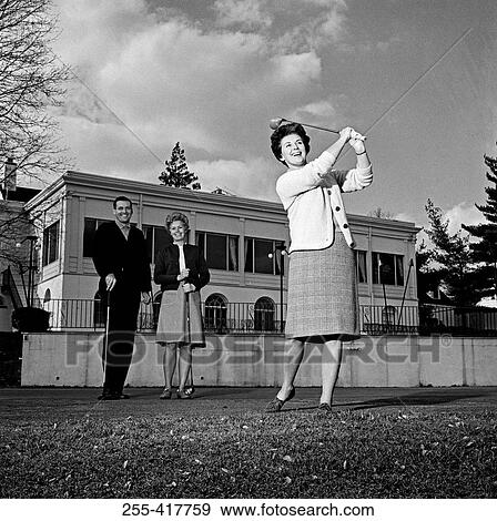 Stock Photo - Mature woman plying golf while pair of people is watching. Fotosearch