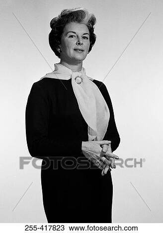 Stock Image - Mature woman standing with hands clasped, portrait. Fotosearch
