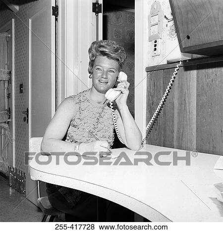 Stock Photo - Mid adult office worker using telephone. Fotosearch