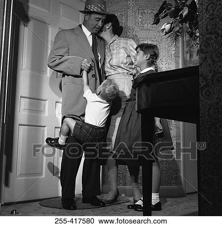 Stock Image - Mother and children with father in entrance hall. Fotosearch