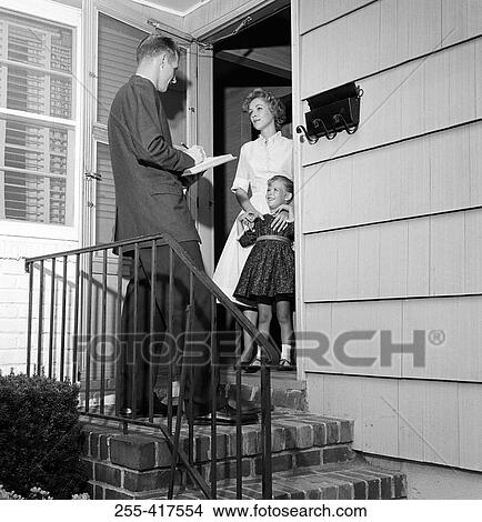 Picture - Mother and daughter answering pollster's questions in doorway. Fotosearch