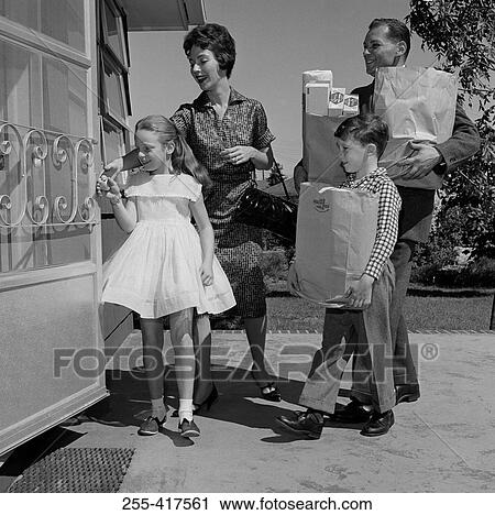 Stock Image - Parents and kids arriving home with shopping. Fotosearch