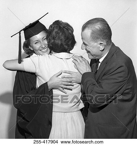 Picture - Parents embracing daughter at graduation. Fotosearch