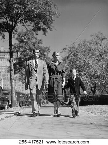 Stock Image - Parents with son walking through park. Fotosearch