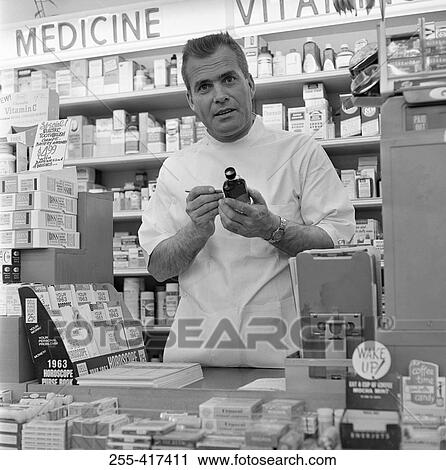 Pharmacist in drug store holding bottle and looking at camera View Large Photo Image Stock Image - Pharmacist in drug store holding bottle and looking at camera. Fotosearch