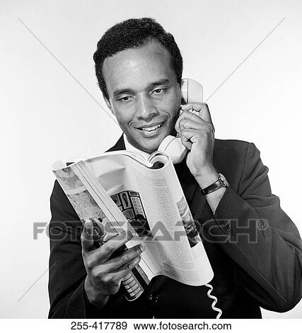 Portrait of African american man holding receiver and reading magazine, studio shot View Large Photo Image Stock Photo - Portrait of African american man holding receiver and reading magazine, studio shot. Fotosearch