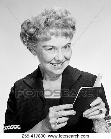 Stock Image - Portrait of happy mature woman holding passport, studio shot. Fotosearch
