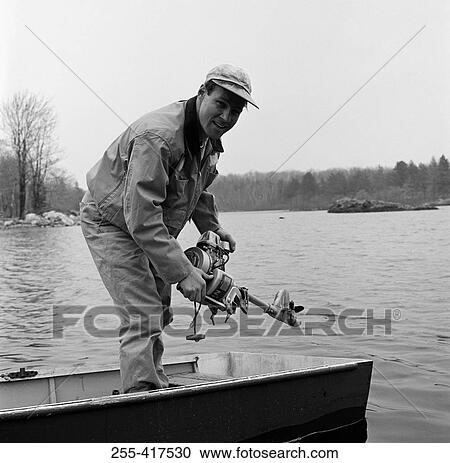 Stock Image - Portrait of man in boat holding engine. Fotosearch