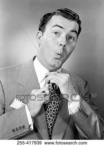 Stock Photo - Portrait of mid adult businessman adjusting tie. Fotosearch