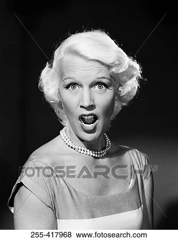 Stock Photo - Portrait of mid adult woman with mouth open and raised eyebrows. Fotosearch