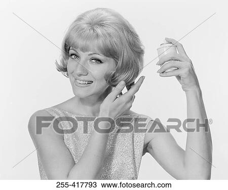 Stock Image - Portrait of young woman making hairstyle, studio shot. Fotosearch