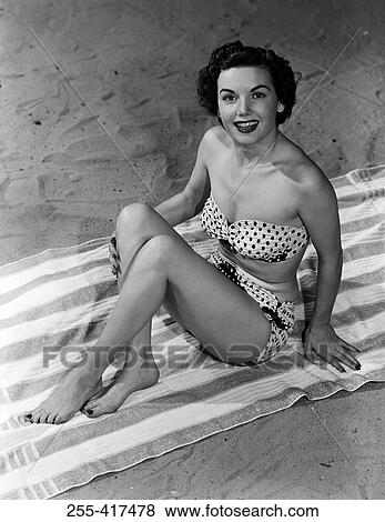 Stock Photo - Portrait of young woman sitting on beach. Fotosearch