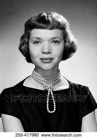 Stock Image - Portrait of young woman wearing pearl necklace. Fotosearch