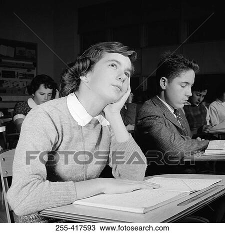 Stock Image - School girl daydreaming in classroom. Fotosearch