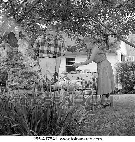 Stock Image - Senior couple having barbecue in backyard. Fotosearch