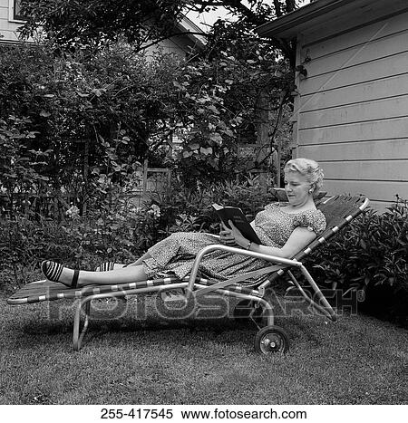 Stock Photography - Senior woman lying on chair reading book. Fotosearch