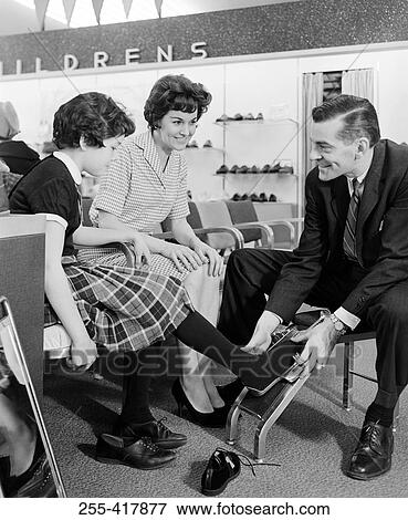 Shop assistant measuring girls foot in shoe shop View Large Photo Image Stock Photo - Shop assistant measuring girls foot in shoe shop. Fotosearch