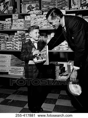 Stock Image - Shop assistant serving boy in toy shop. Fotosearch