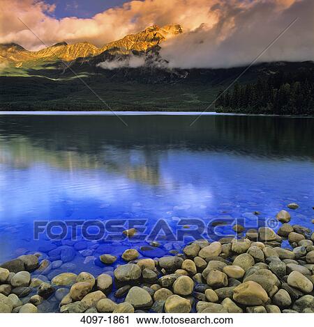 Stock Image - Stones in a lake with mountains in the background, Pyramid Lake, Pyramid Mountain, Jasper National Park, Alberta, Canada. Fotosearch