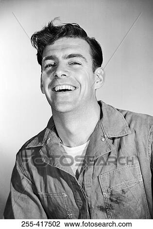 Stock Image - Studio portrait of mid adult man in coveralls. Fotosearch