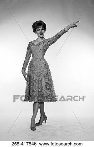 Stock Photograph - Studio portrait of woman pointing upward. Fotosearch